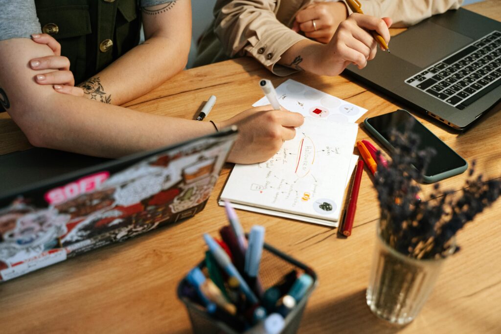 Two people collaborating in a modern workspace with laptops and notes.