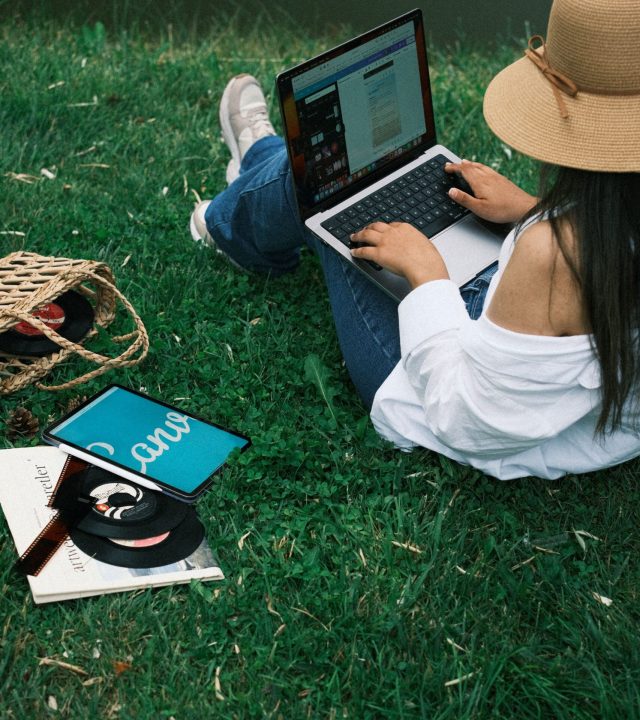 Young woman working on a laptop in the park, surrounded by nature and relaxation.